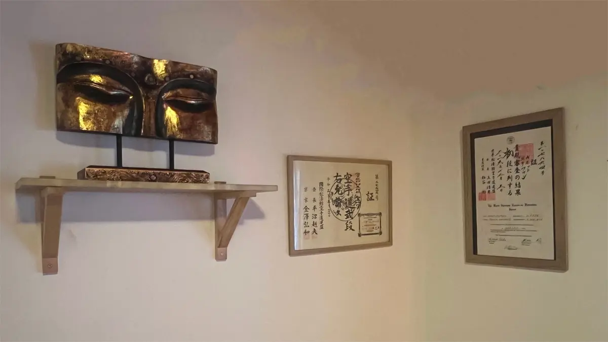 Gros plan sur les yeux d’un Bouddha avec deux diplômes japonais de shiatsu exposés à côté